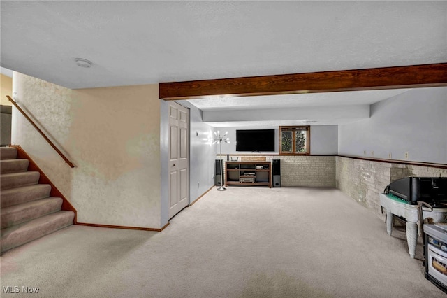 unfurnished living room featuring stairway, beamed ceiling, wainscoting, and light colored carpet