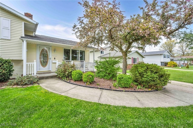 split level home with a porch, a chimney, and a front yard