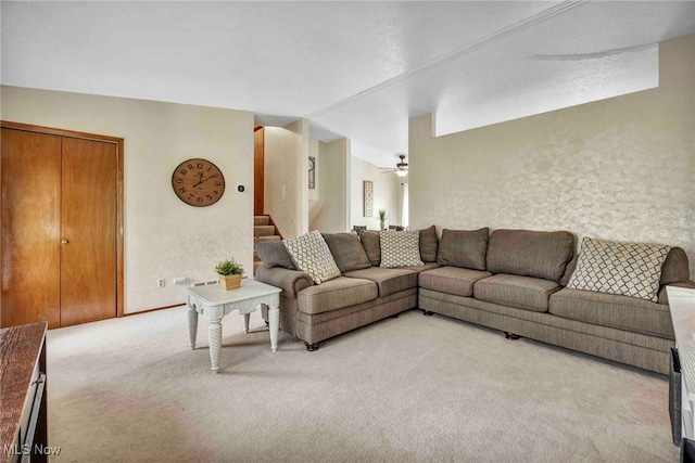 living room featuring stairs, a ceiling fan, and light carpet