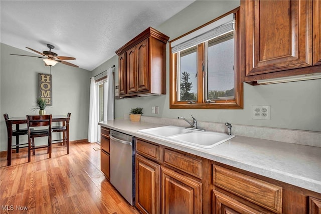 kitchen with brown cabinetry, light wood-type flooring, a sink, and dishwasher