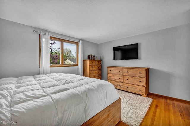 bedroom featuring wood-type flooring, a textured ceiling, and baseboards