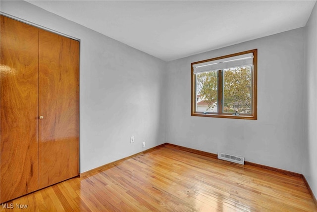 unfurnished bedroom featuring baseboards, visible vents, light wood-style flooring, and a closet