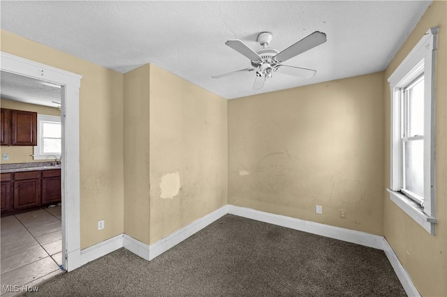empty room with baseboards, ceiling fan, and light colored carpet