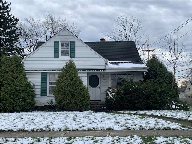 view of front of home with a shingled roof and a chimney