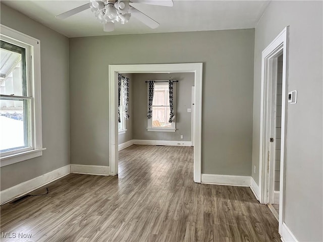 unfurnished room with plenty of natural light, baseboards, ceiling fan, and wood finished floors