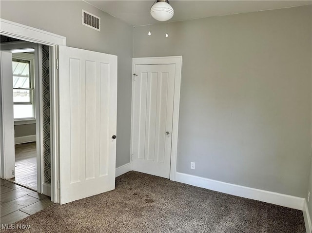 unfurnished bedroom featuring baseboards, carpet flooring, and visible vents