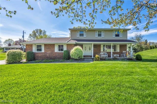 traditional home featuring a porch, brick siding, and a front yard