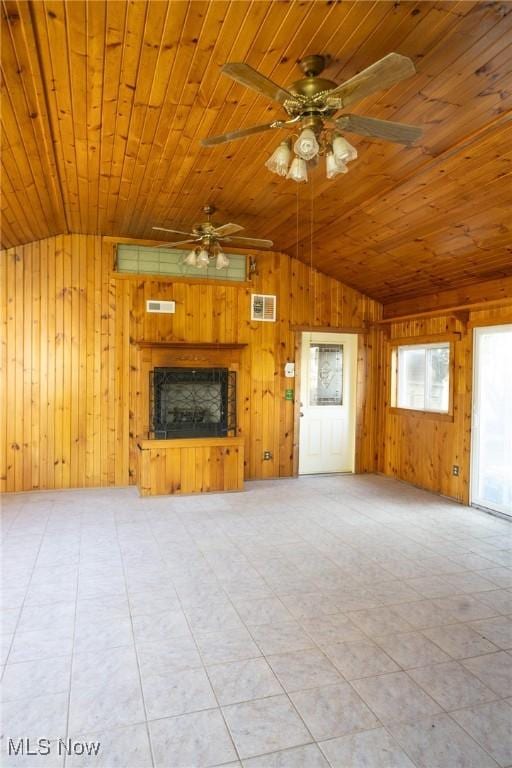 unfurnished living room featuring visible vents, lofted ceiling, ceiling fan, wooden walls, and wooden ceiling