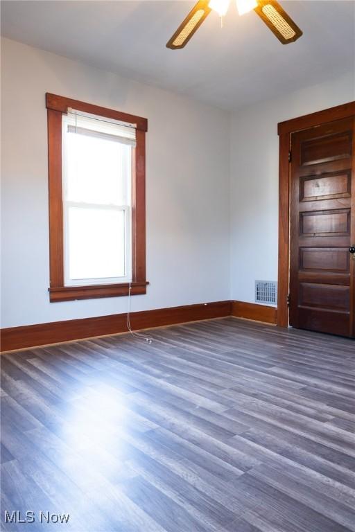 empty room featuring baseboards, visible vents, ceiling fan, and wood finished floors