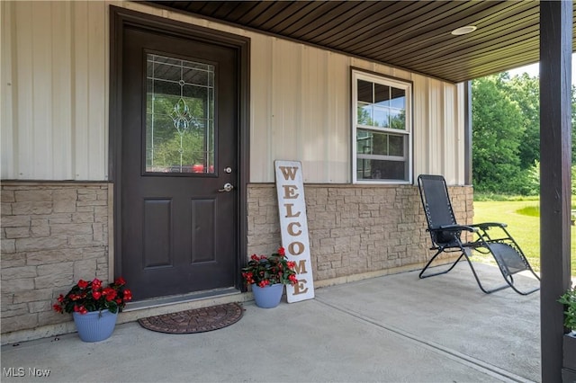 entrance to property featuring covered porch and stone siding