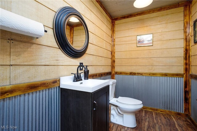 bathroom featuring vanity, wood finished floors, wooden walls, and toilet