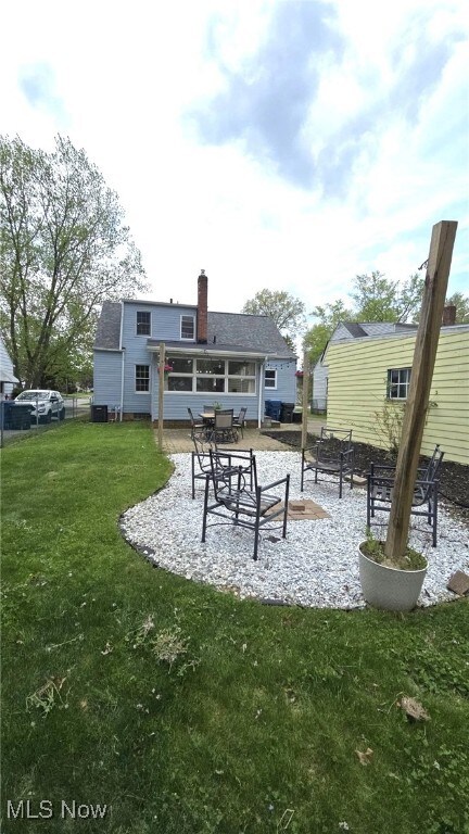 22322 Westwood Rd, Fairview Park, OH 44126 - rear view of property featuring a patio, a lawn, fence, and a chimney