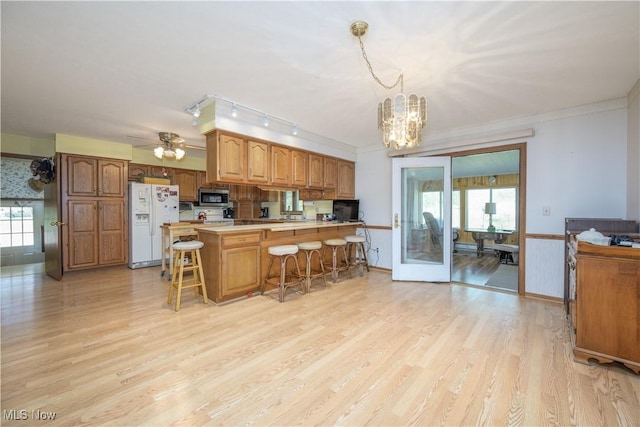 4561 Industry Rd, Ravenna, OH 44266 - kitchen with light countertops, stainless steel microwave, a peninsula, a chandelier, and white fridge with ice dispenser