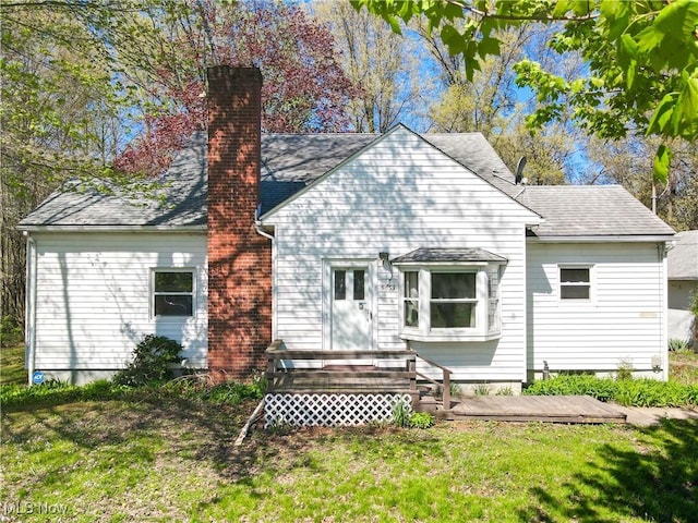 rear view of property with a wooden deck, a chimney, and a yard