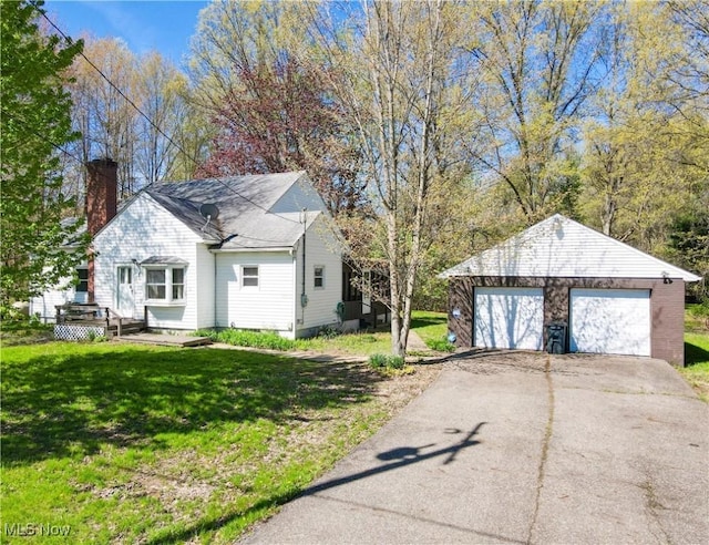 view of property exterior featuring a yard, an outbuilding, a chimney, and a detached garage