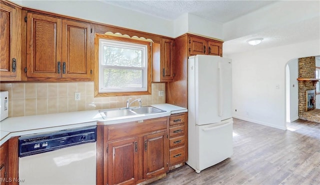 kitchen featuring a sink, decorative backsplash, white appliances, and light countertops