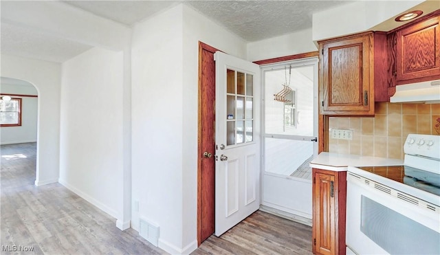 kitchen with white electric range oven, extractor fan, light wood-style flooring, backsplash, and visible vents