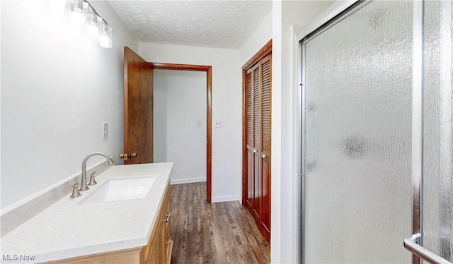 bathroom featuring a textured ceiling, a stall shower, wood finished floors, vanity, and a closet