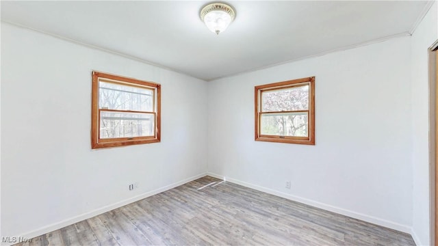 spare room featuring plenty of natural light, light wood finished floors, and baseboards