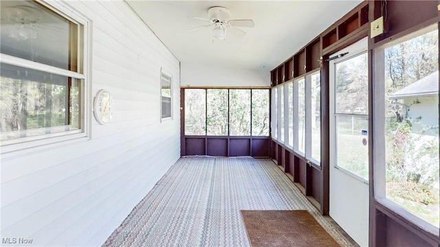 unfurnished sunroom featuring ceiling fan and a healthy amount of sunlight