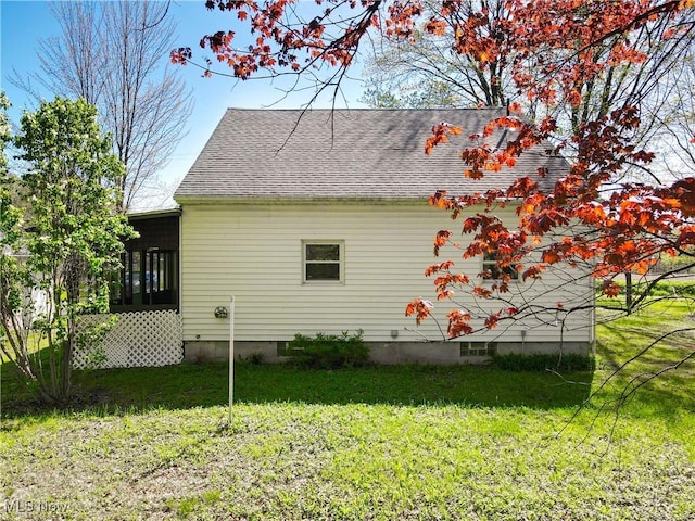 view of property exterior with a lawn, a shingled roof, and a sunroom
