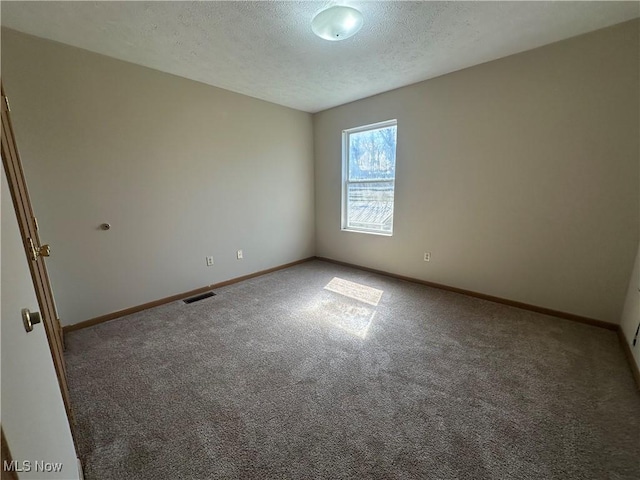 carpeted spare room featuring baseboards, a textured ceiling, and visible vents