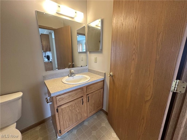 half bath with vanity, baseboards, and toilet