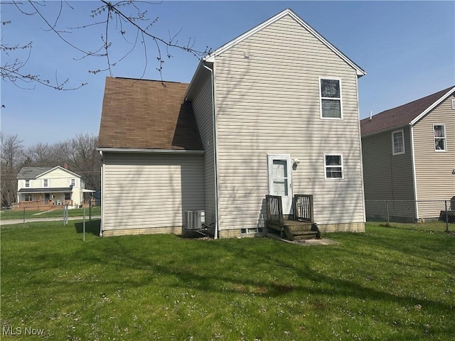 back of property with central AC unit, fence, and a yard