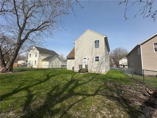rear view of house featuring entry steps, a yard, and a fenced backyard