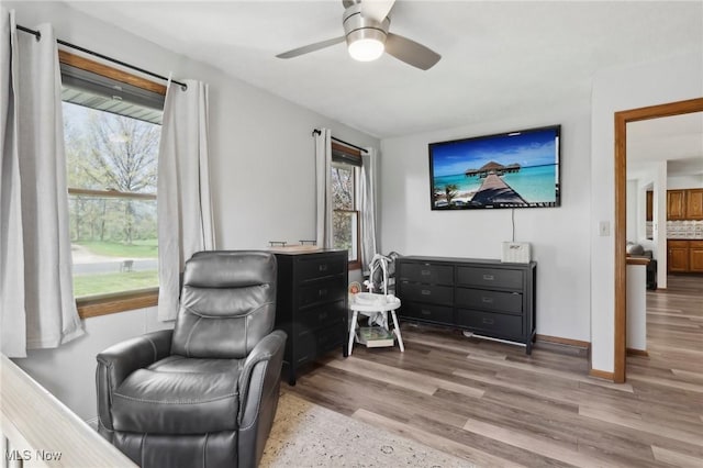 living area featuring baseboards, ceiling fan, and wood finished floors