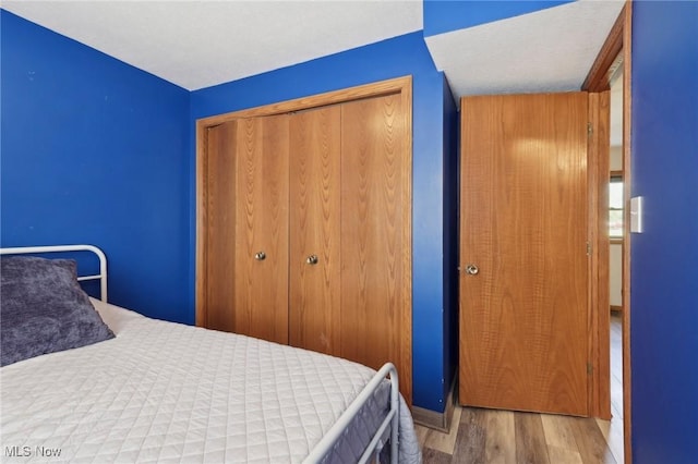 bedroom with baseboards, a closet, and wood finished floors