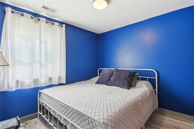 bedroom featuring baseboards, wood finished floors, and visible vents