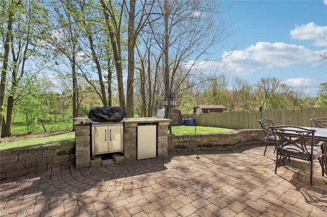 view of patio / terrace featuring a storage unit, fence, an outbuilding, and outdoor dining space
