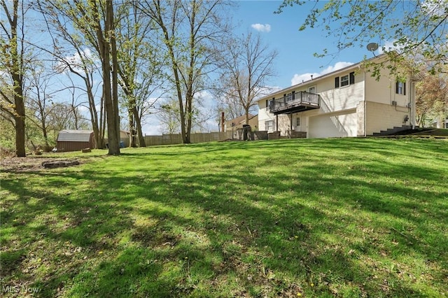 view of yard with fence, a balcony, an attached garage, a storage shed, and an outbuilding