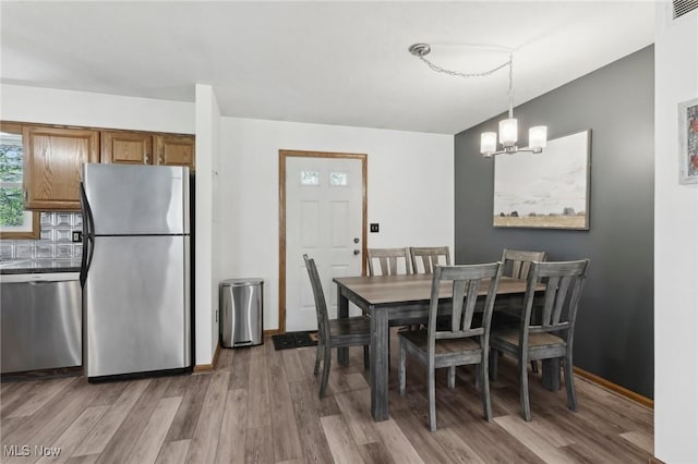 dining room featuring baseboards, an inviting chandelier, wood finished floors, and visible vents