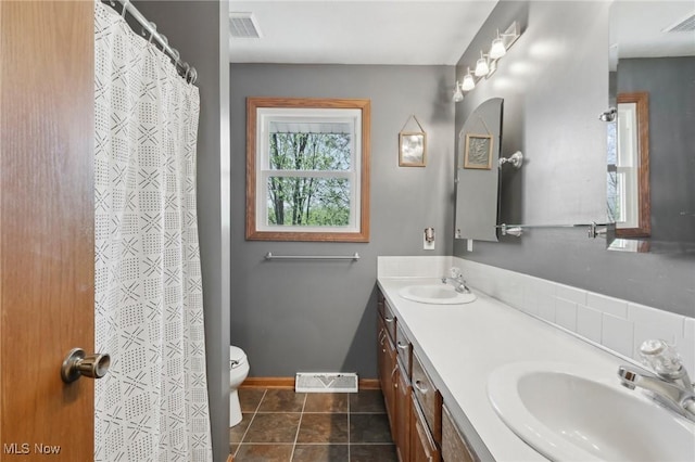 bathroom featuring toilet, visible vents, and a sink