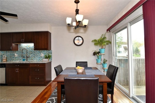dining space with light wood-type flooring, a textured ceiling, and ceiling fan with notable chandelier