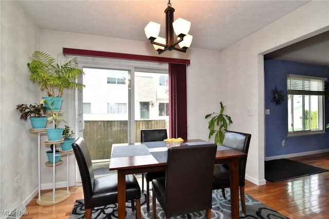 dining space featuring an inviting chandelier, baseboards, and wood finished floors
