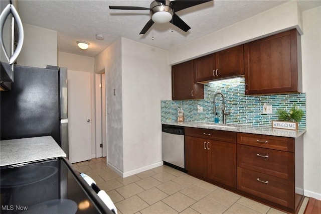 kitchen featuring decorative backsplash, a ceiling fan, baseboards, a sink, and stainless steel appliances