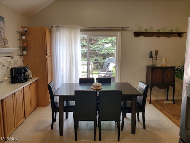 dining room featuring baseboards, light tile patterned floors, and vaulted ceiling