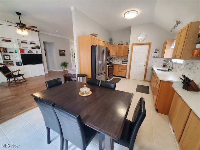 dining room with ceiling fan, vaulted ceiling, and light tile patterned floors