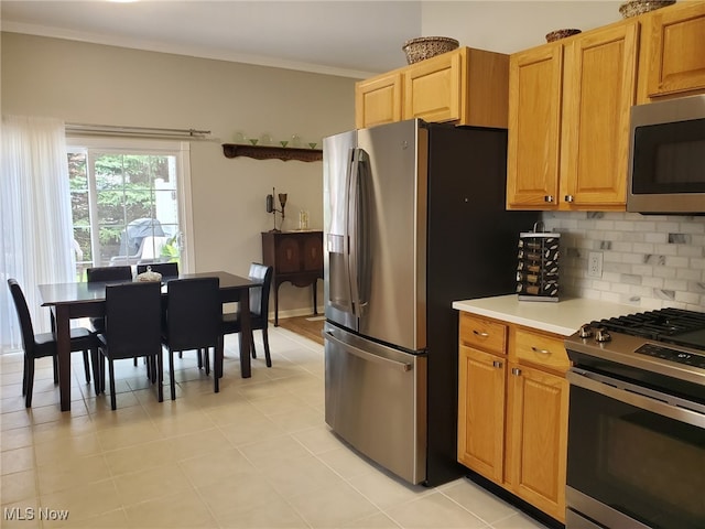 kitchen with crown molding, appliances with stainless steel finishes, light countertops, decorative backsplash, and light tile patterned floors