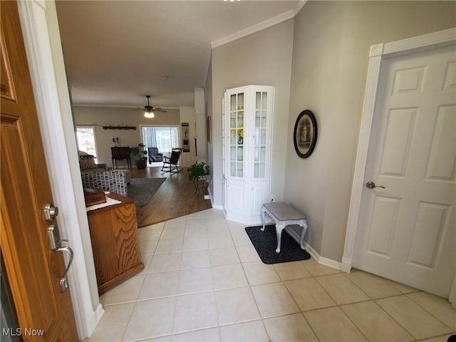 entrance foyer featuring baseboards, ceiling fan, ornamental molding, and light tile patterned floors
