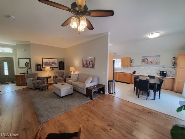 living area with light wood-style floors, ornamental molding, and ceiling fan