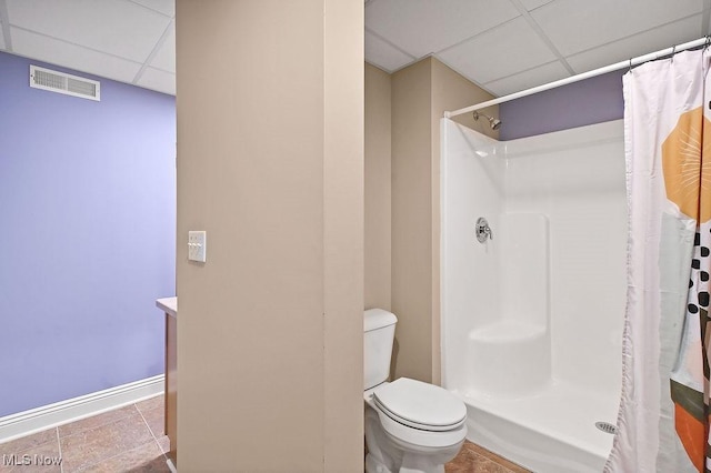 bathroom with a drop ceiling, toilet, curtained shower, and visible vents