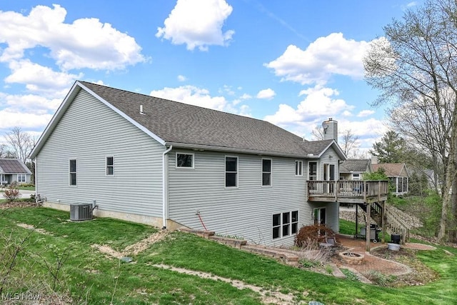 back of property featuring a fire pit, a deck, a chimney, central AC unit, and a yard