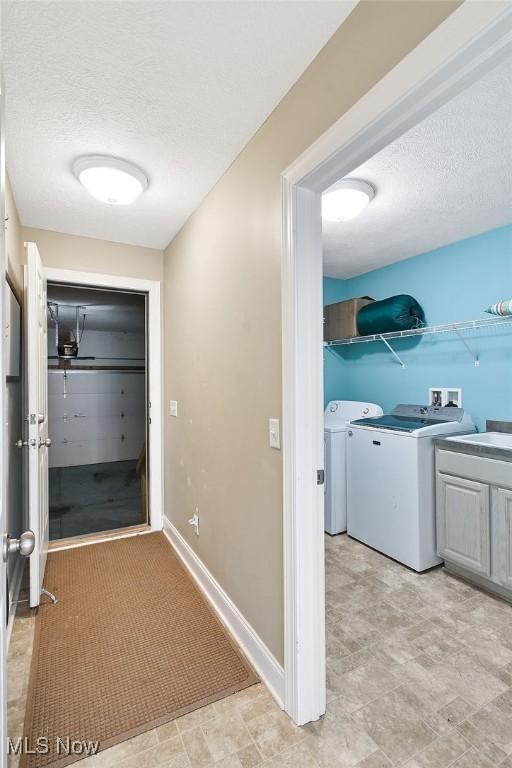 hall featuring baseboards, independent washer and dryer, and a textured ceiling