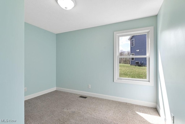 carpeted spare room with baseboards and visible vents