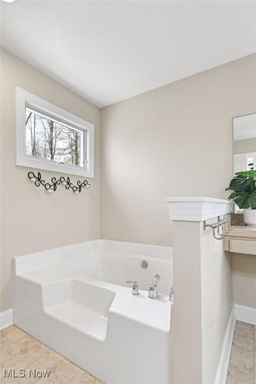 full bath featuring baseboards and a bath