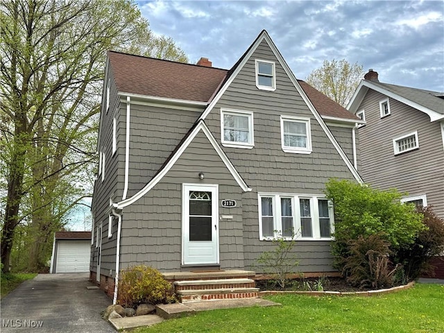 view of front of house featuring an outdoor structure, a garage, a front lawn, and entry steps